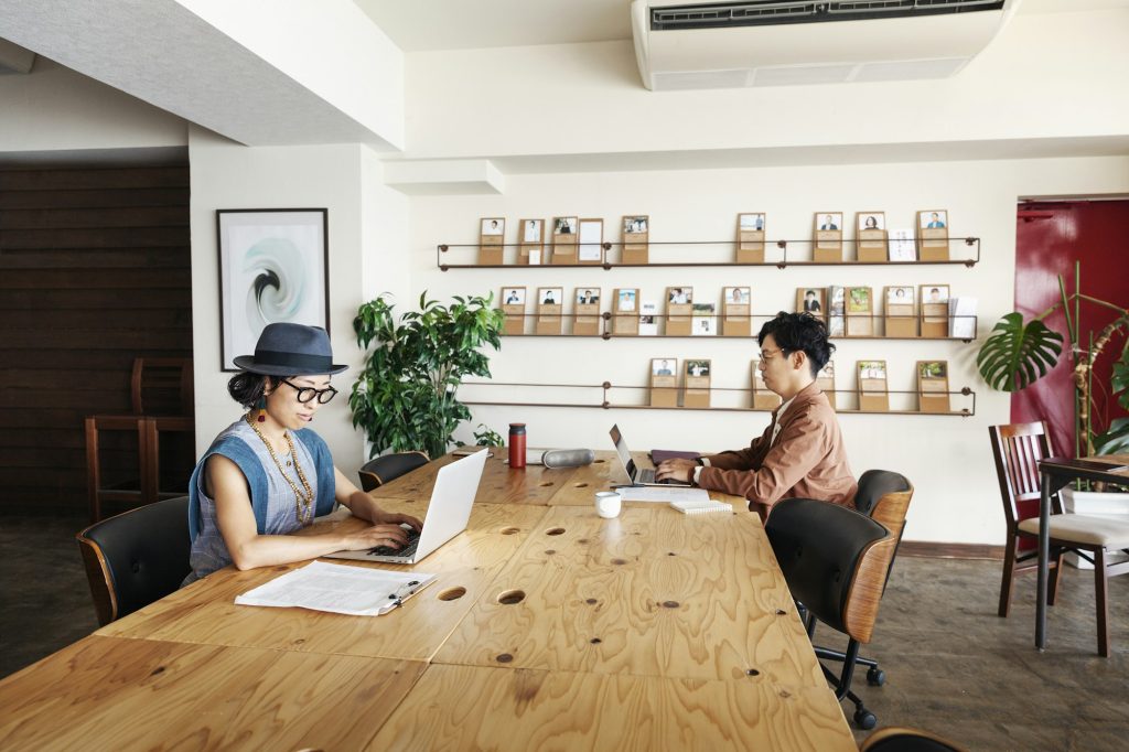 Group of young Japanese professionals working on laptop computers in a co-working space.